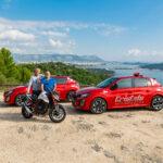 2 moniteurs de l'auto-moto école Cristale à la Seyne-sur-Mer derrière une motocyclette et devant 2 automobiles rouges sur un parking surplombant la rade de Toulon