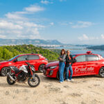 2 monitrices de l'auto-moto école Cristale à la Seyne-sur-Mer devant 2 automobiles rouges et une motocyclette sur un parking surplombant la rade de Toulon